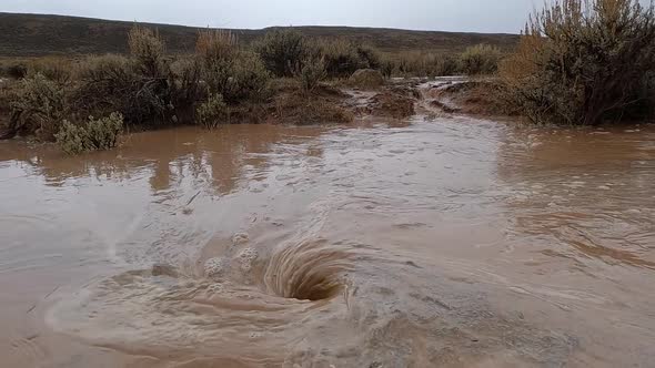 Whirlpool of muddy rain water in the desert after heavy storm in Wyoming alt