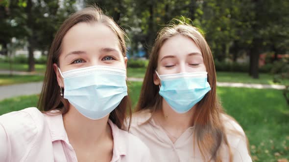 Happy young women students wearing medical face masks talking video calling on chatting. alt