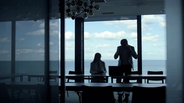 Two Silhouettes Shaking Hands in Modern Hall alt