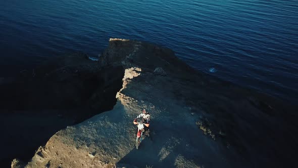 Drone View of Man on Motorbike Extremely Rides Across the Hills with Black Sea on Background in