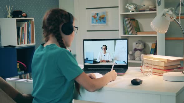 Schoolgirl Studying Remotely in Her Room Using a Laptop alt