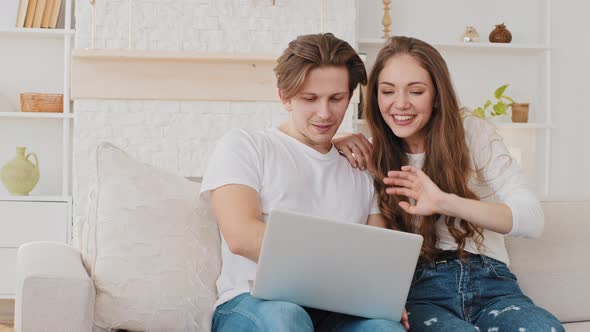 Happy Caucasian Millennial Couple Husband and Wife Making Video Call Remotely From Home on Couch alt