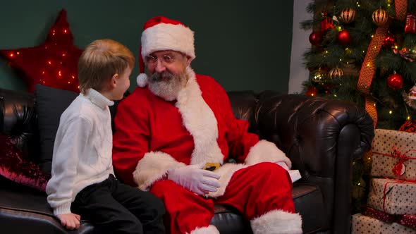 Santa Claus Gives a Cherished Gift to a Little Boy the Child Rejoices and Hugs the Magic Grandfather alt