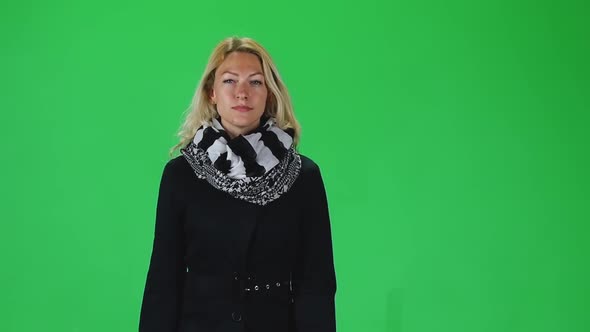 Blonde Girl in a Black and White Scarf and Coat Going Against a Green Screen. Slow Motion alt