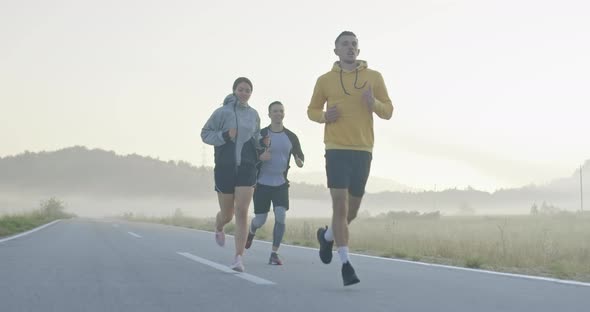 Multiethnic Group of Athletes Running Together on a Panoramic Countryside Road