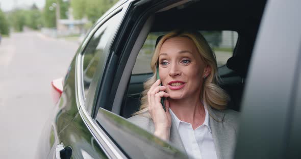 Woman Rides on Rear Passenger Seat of Car, Looking Wonder Out of the Window During Phone Call alt