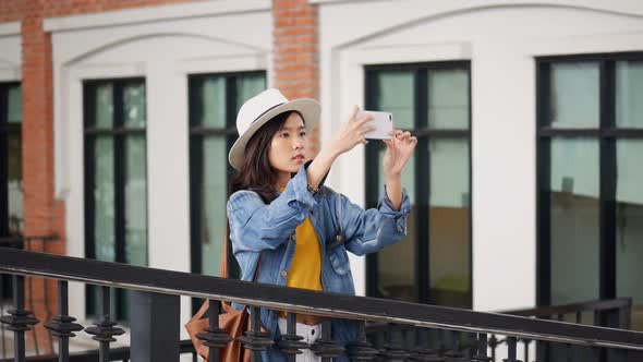 Young Asian woman using smartphones take photos around community malls.