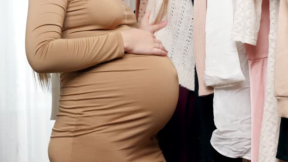 Closeup of Beautiful Pregnant Woman Having Shopping and Looking for Maternal Clothes To Buy alt