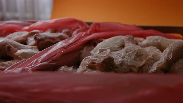 Closeup View of Hands in Gloves Packing Chicken Legs From a Box Into Individual Plastic Bags alt