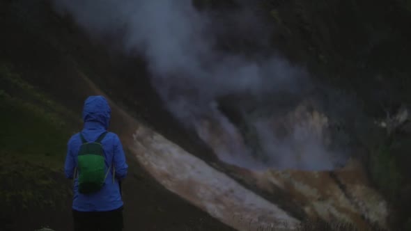 iceland landscape, geothermal hotspring steam smoke, one person watching the smoke rising, camera ti alt