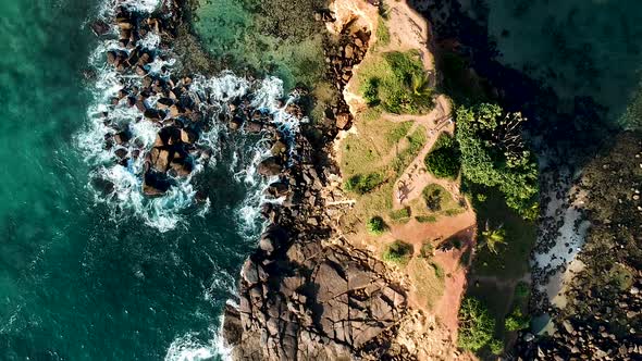 Aerial drone of Mirissa Beach at sunset golden hour. Parrot Rock with waves on sandy beach. Mirissa, alt