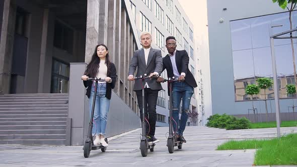 Young Mixed Race Friends in Stylish Wear Which Riding on Electric Scooters alt