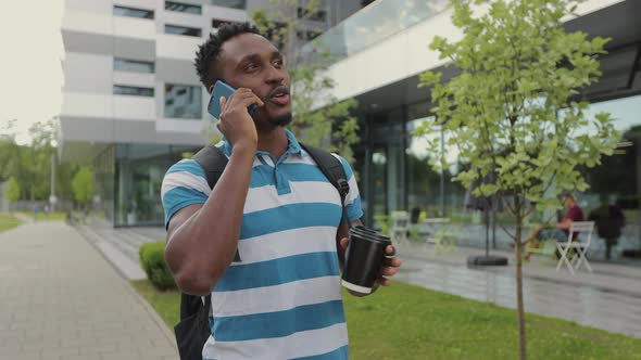 Portrait of African American Man in Casual Clothes in City Talking on Smart Phone alt