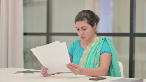 Indian Woman Reading Reports While Sitting in Office alt