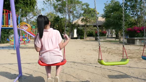 Sad Asian Girl Playing Swing In The Park alt