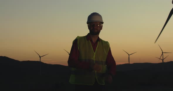 A Young Engineer Turns Towards the Camera at Sunset Laying His Hands on Each Other alt