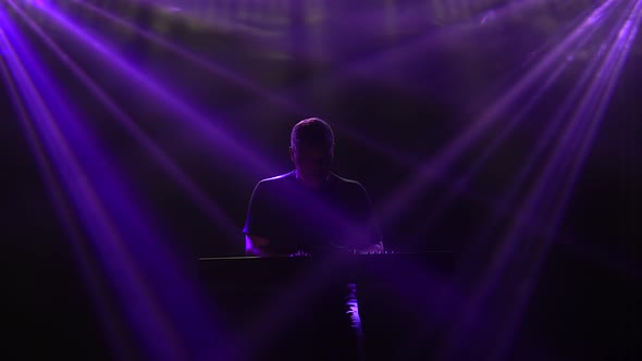 Musician Silhouette Playing on Synthesizer Piano Keyboard in Dark Studio with Neon Lighting. Dynamic alt