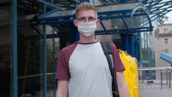 Rack Focus From Male Courier in Eyeglasses and Coronavirus Face Mask to Stretched Package with alt