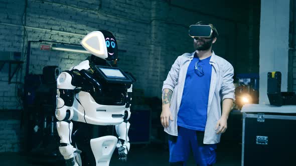 Robotics Engineer in VRglasses Is Operating a Modern Cyborg Robot alt