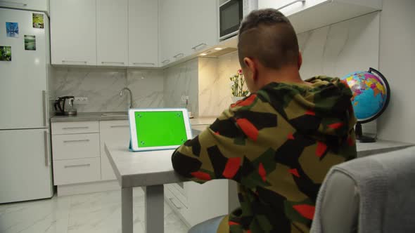 Kid Scrolling Chroma Key Green Screen on Digital Tablet Indoors alt