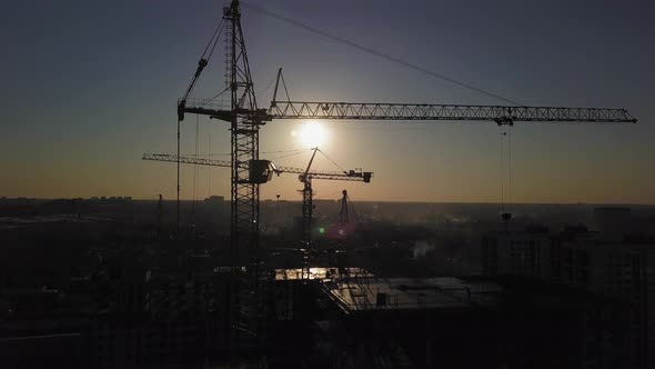 Construction Site at Sunset. Silhouette of a Construction Crane Near the Building