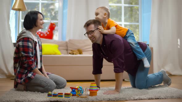 Father, Mother and Son Playing on the Floor in Living Room. alt