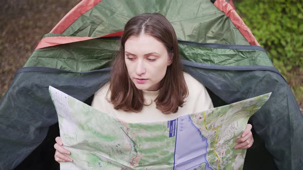 A Young Woman with a Map in a Tent