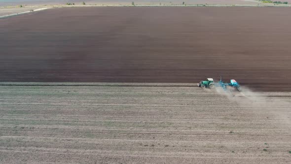 Aerial Shot of a Wide Agriculture Field with a Tractor Ploughing It in Autumn  