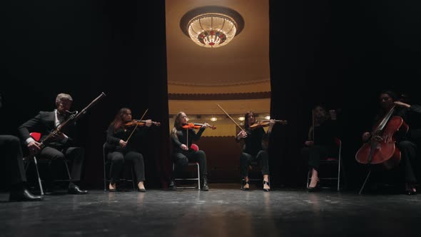 Musical Ensemble of String and Wind Instrument on Scene of Old Opera House Curtain is Opening alt