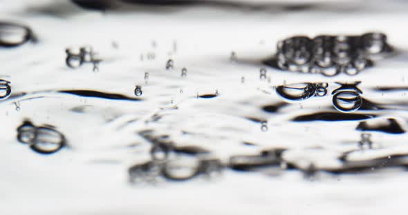 Lockdown Shot Of Bubbles Floating To Water Surface Against White Background alt