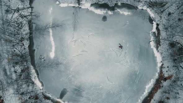 Drone looking down towards a single player playing ice hockey on a frozen pond or lake in Canada. alt