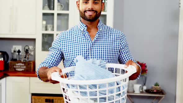 Portrait of happy man holding bucket full of clothes alt