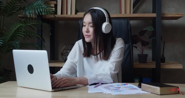 Tired Young Asian Business Woman Wearing Headphones Communicating End of the Working Day alt