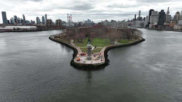 An aerial view of the Roosevelt Island lighthouse on a cloudy day. The camera truck left, pan right alt