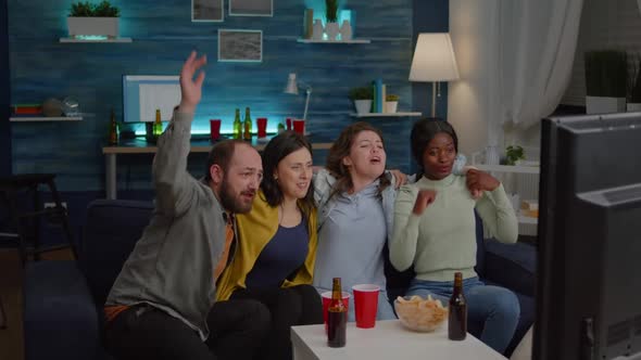 Group of Multiracial People Cheering Football Team While Sitting on Couch alt