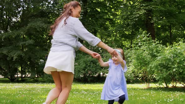 Happy Mother with Little Daughter Dancing at Park