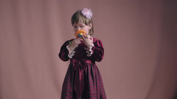 Little Girl in Vintage Burgundy Dress Angry Naughty Throws Toy Rattle on Floor