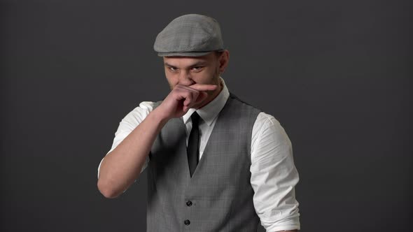 Portrait of Dangerous Criminal Man in Retro Suit and Kepi Wiping His Nose After Fighting Over Gray alt