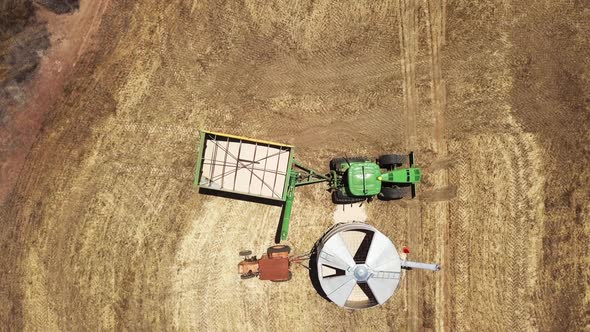 Tractor pulls up to a grain silo to unload its cargo of harvested corn - aerial straight down view alt