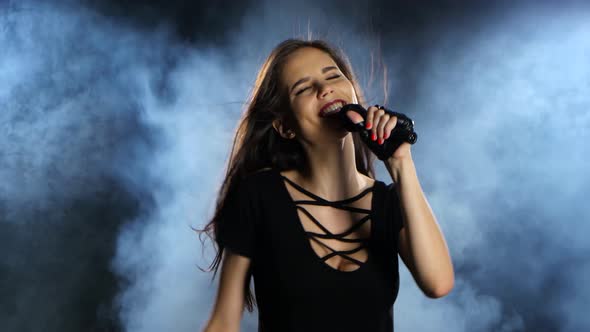 Singer Sexually Dances and Sings Songs in a Microphone at a Concert. Black Smoke Background alt