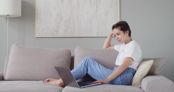 Young Lady Sitting on Sofa Using Laptop with Happy Expression Copy Space Text