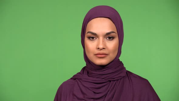 A Young Beautiful Muslim Woman Looks Seriously at the Camera  Closeup  Green Screen Background