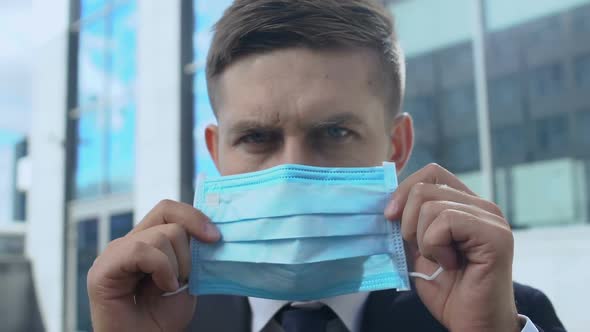 Concerned Man Putting on Facemask in Street Close-Up, Ecology Problems Awareness