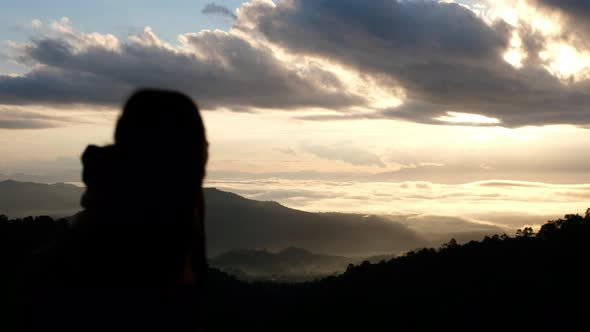 Silhouette blurred of a female traveler looking at a beautiful mountains view on foggy day