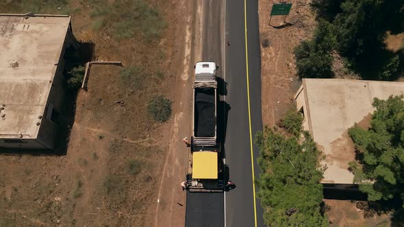 Asphalt paving machine escorted by an Asphalt truck at work, Top down aerial view. alt