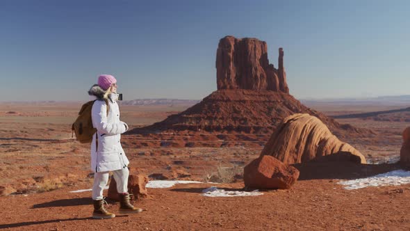 Camera Following Female in White Coat with Backpack Walking By Red Desert Nature alt