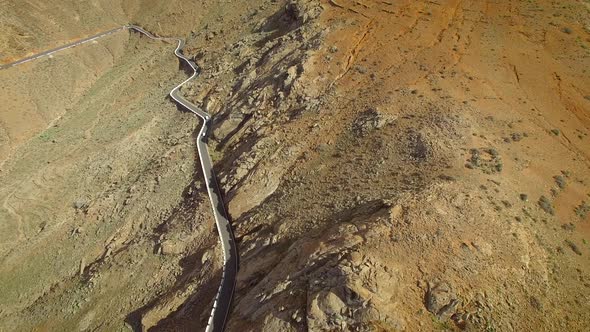 Aerial view of a car driving on a winding mountain road in Fuerteventura. alt