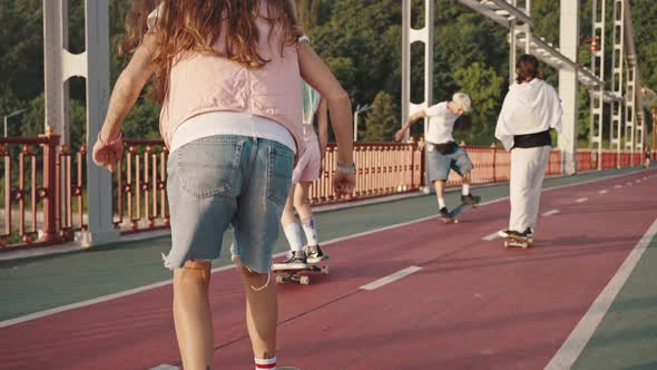 Teenagers Skate on the Bridge Rear View alt