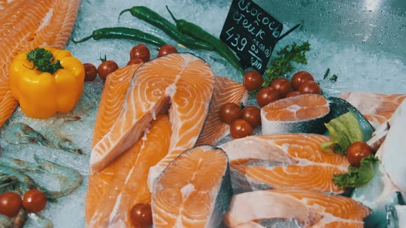 Composition of Trout and Salmon Steaks Lies on Ice in Showcase of Supermarket alt