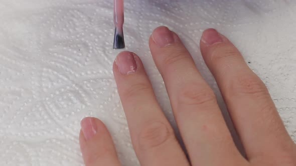 Young Woman Paints Her Nails with Natural Pink Gel Base. Nails Manicure. Close Up Hands